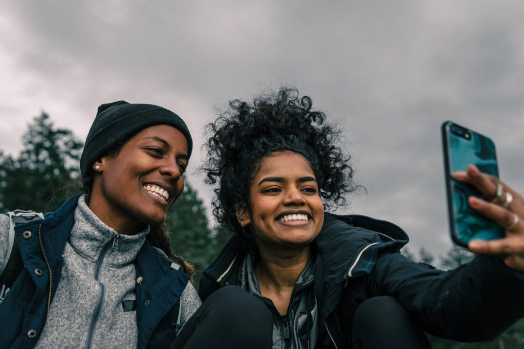 Two women joyfully capturing a selfie in an outdoor setting, showcasing happiness and friendship.